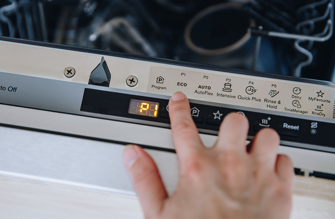 A person selecting a dishwasher cycle on a dishwasher door