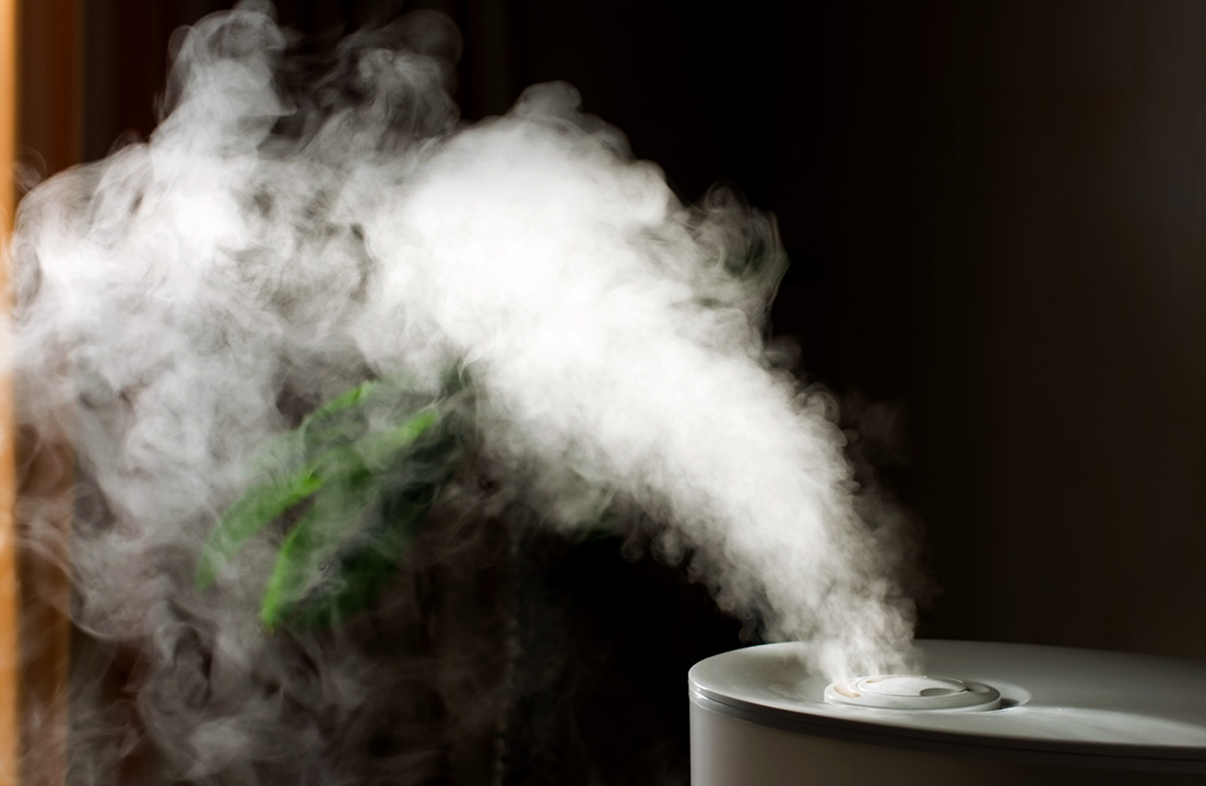 A tabletop humidifier releases a steady stream of mist into the air