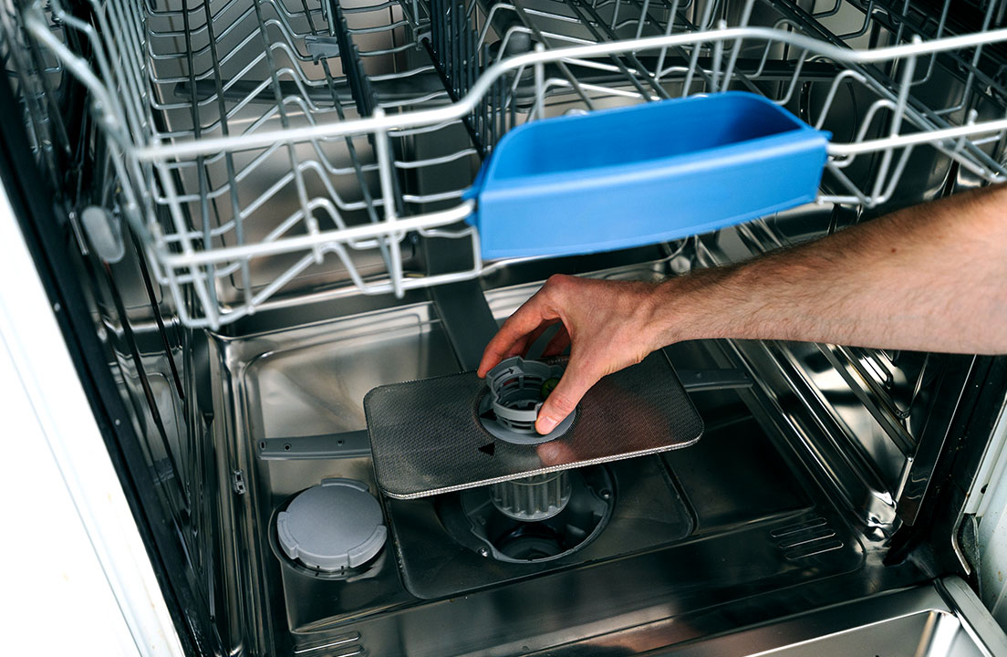 Dishwasher rack with person pulling out a filter showing how loading mistakes and clogged filters can lead to dishes coming out less clean
