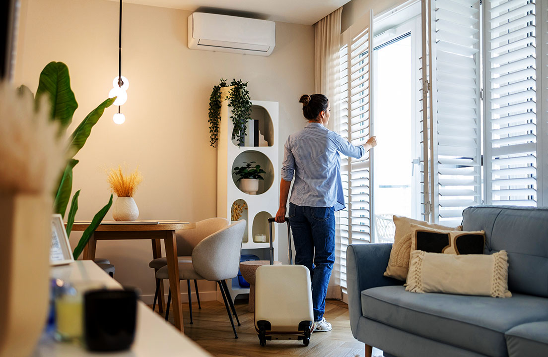 Person opening window shutters before leaving home with a suitcase