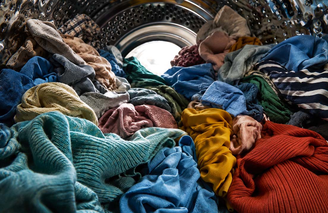 Overloaded washing machine drum packed tightly with clothes