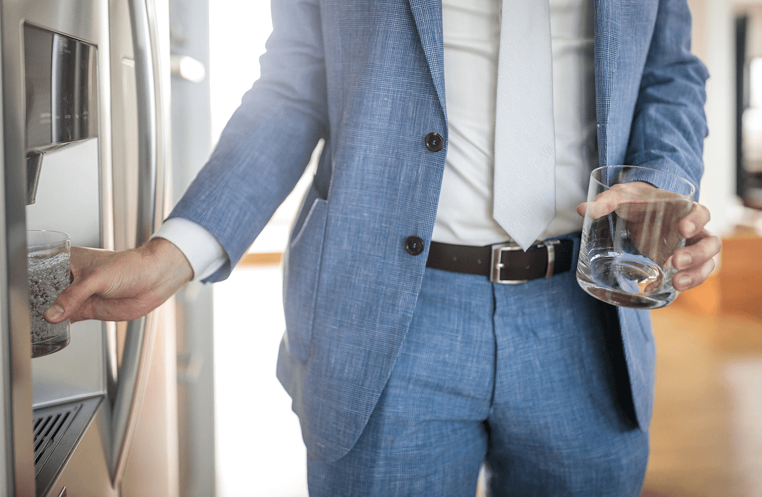 A man getting water from a fridge water dispenser