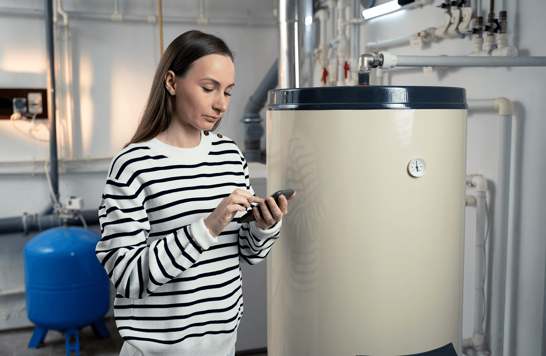 A woman next to a gas furance looking at her smartphone