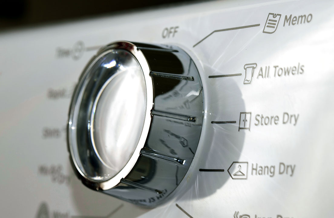 Close-up of a dryer cycle knob with settings like Store Dry and Hang Dry