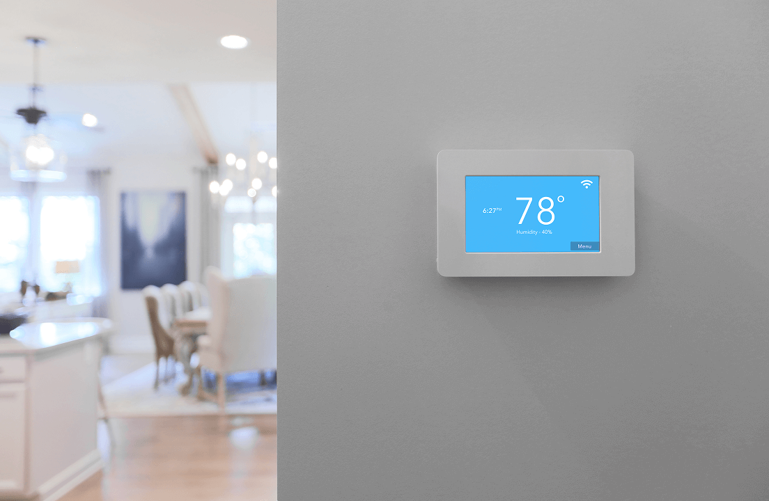 A thermostat on the wall with a blurred background of a kitchen