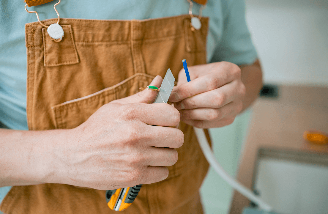 A person stripping the plastic sheathe from a copper wire
