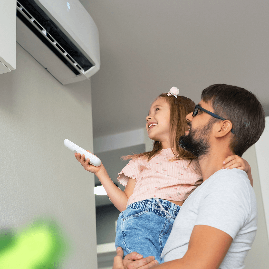 Smiling child being held up by father near an AC unit
