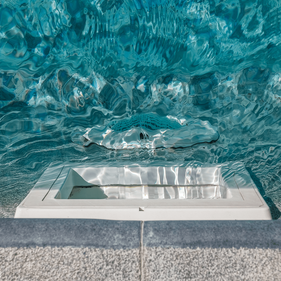 A pool filter opening on the side of a pool