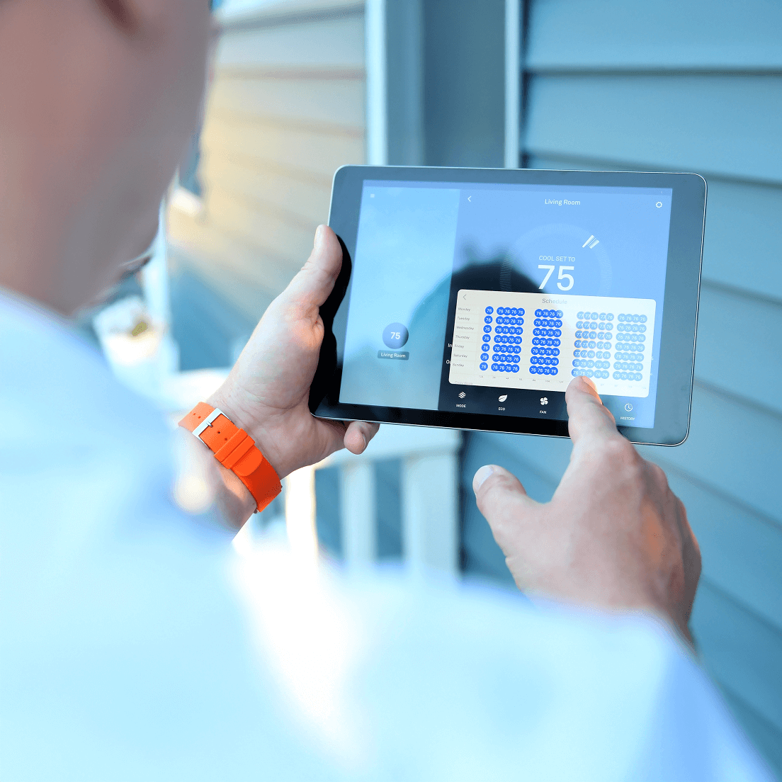 A person using a smart tablet to schedule smart routines within their home on an app