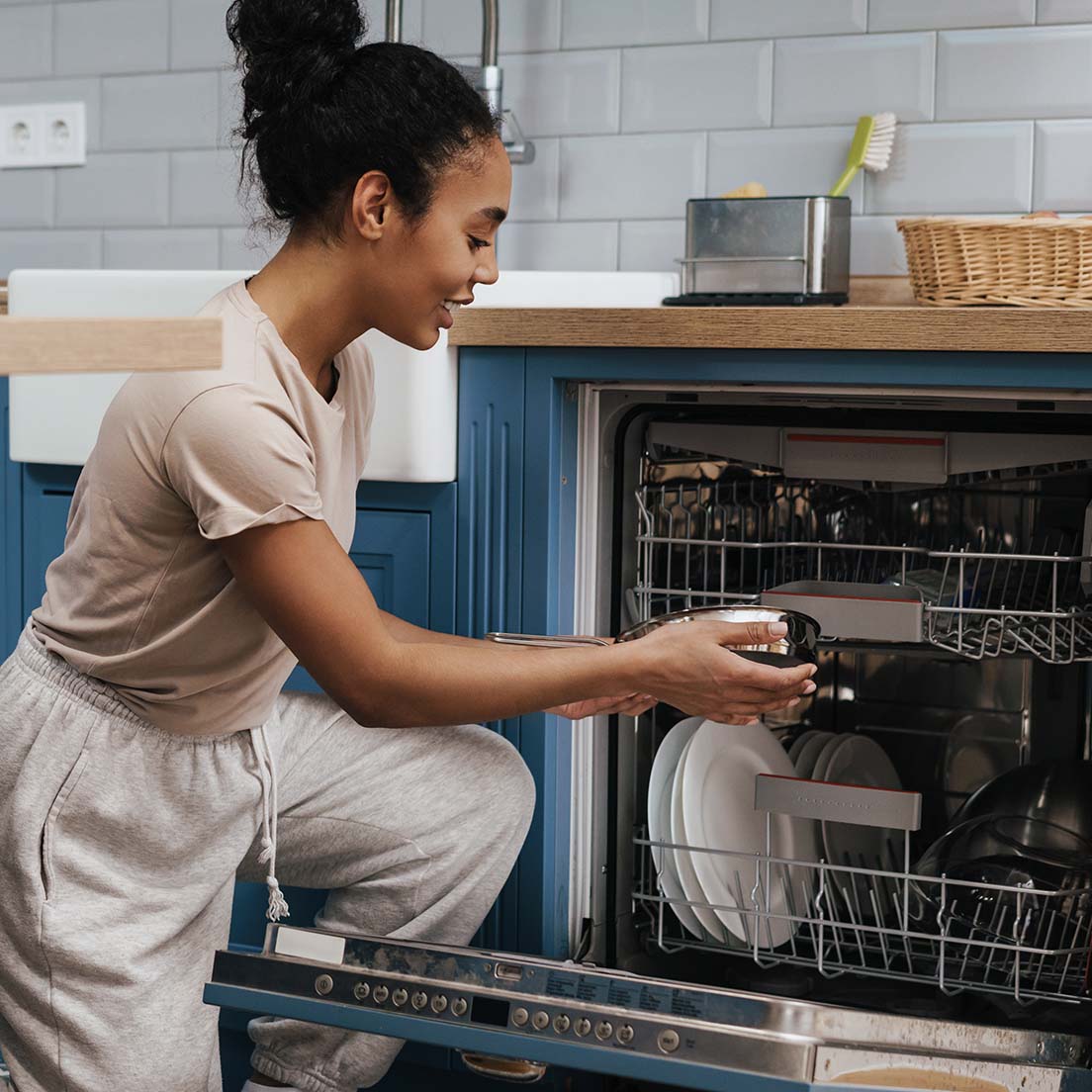 A woman putting away clean dishes from the dishwasher