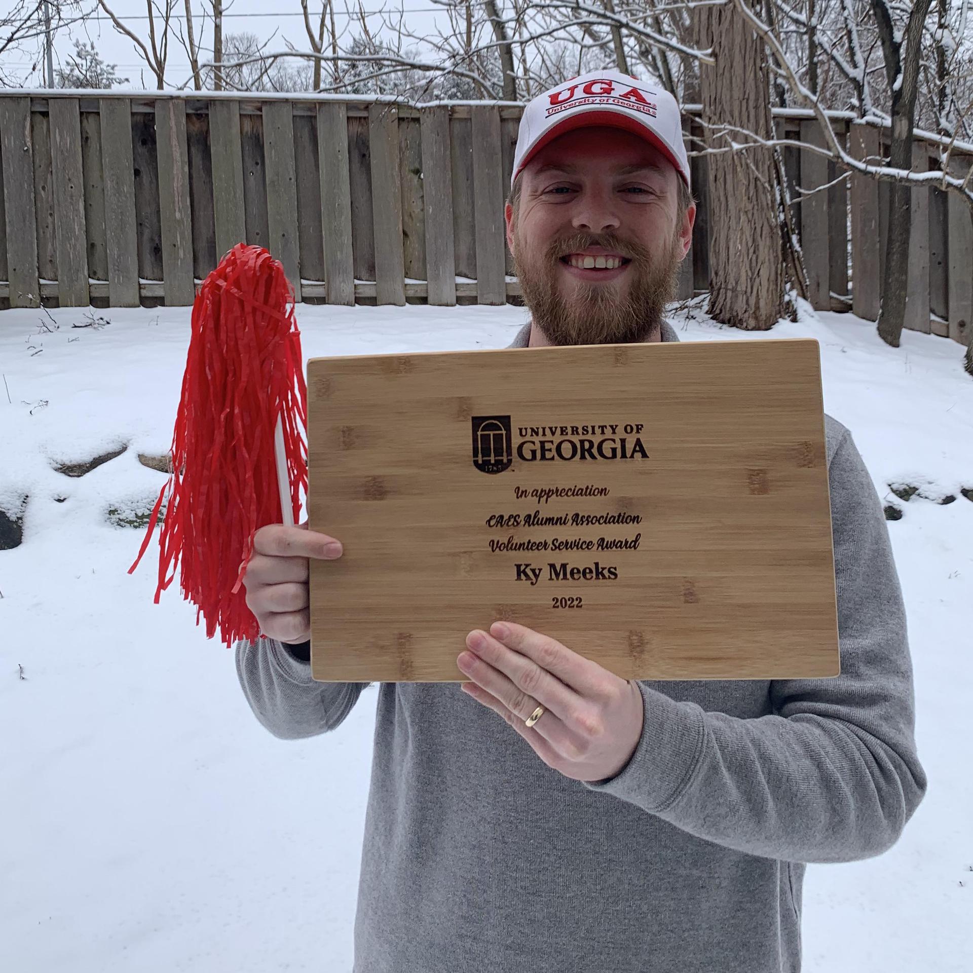 Ky Meeks holding his Volunteer Service Award cutting board