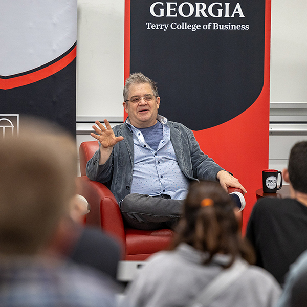 Patton Oswalt sitting in front of Terry College Banners