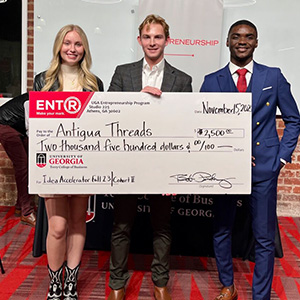 Kelsie Pearson and Juvis Mbeng’s stand with Moss Davis, who is holding a novelty prize check