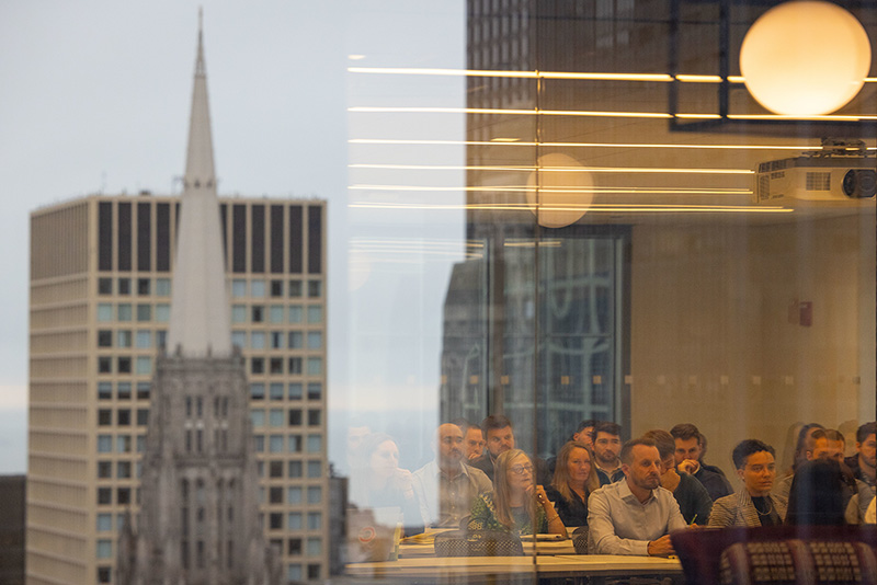 PMBA students sit in class behind a class wall reflecting the Chicago sideline