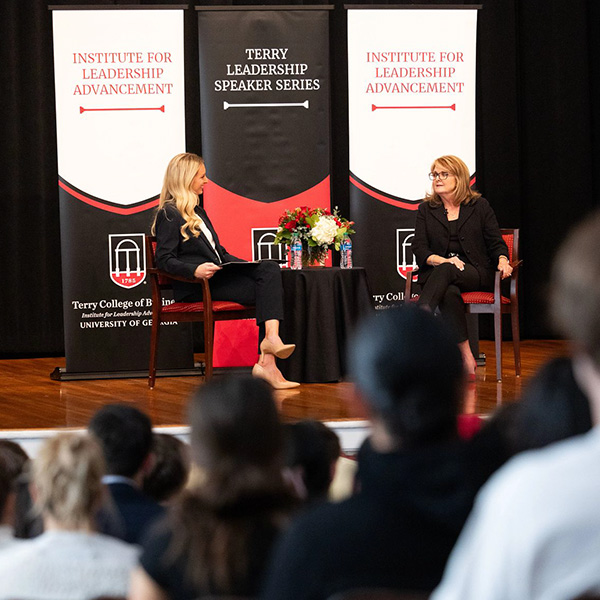 Colleen Langner on stage at the UGA Chapel with Institute for Leadership Advancement behind her and a crowd in the foreground.