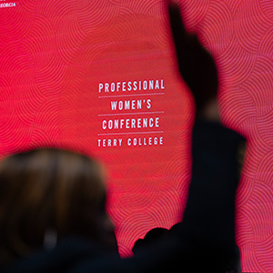 Silhouette of woman raising her hand in front of illuminated red Professional Womens Conference Slide