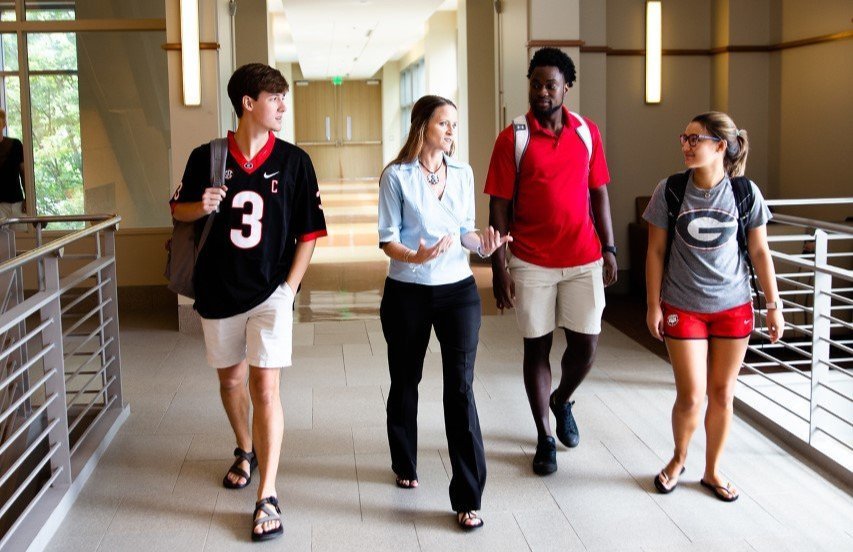 Alumna Susan Kane walks with three pharmacy students