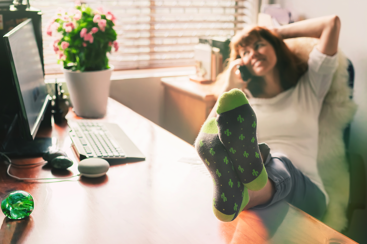 Image of a woman leaning back in an office chair on the phone with her feet up on her desk.